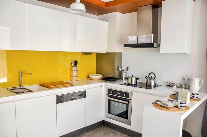 Modern kitchen with white cabinetry and yellow splashback.