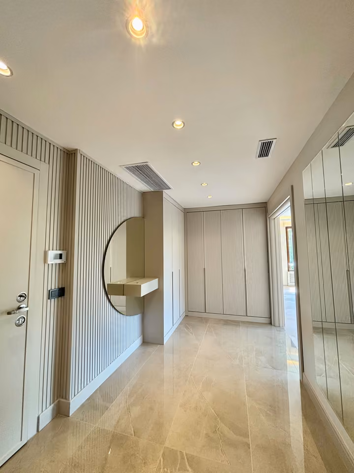 Entrance hall with panelled storage cupboards, a mirror and recessed ceiling lights.