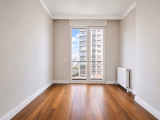 Empty bedroom with wood flooring and a full-height window.