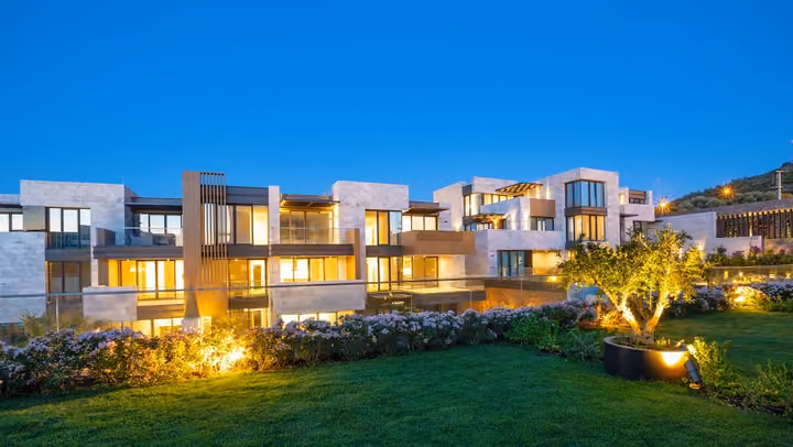 Landscaped garden and illuminated apartment balconies in Boyalik, Cesme.
