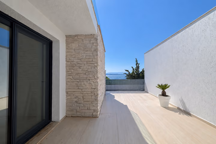Side terrace beside stone-clad walls and sliding glass doors.