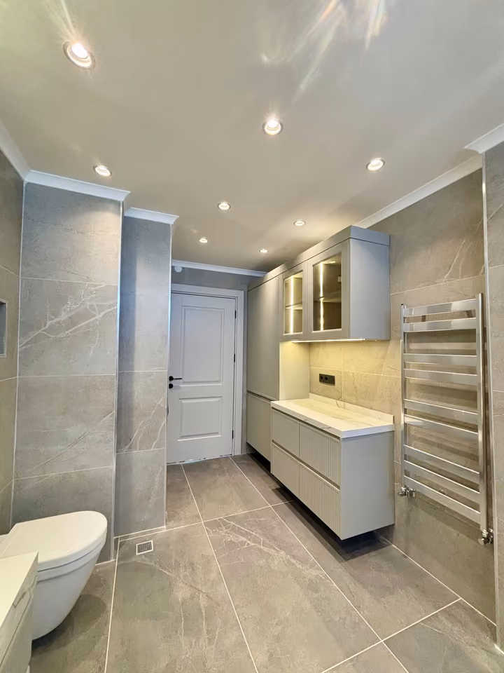 Bathroom storage cabinets and a chrome towel rail.