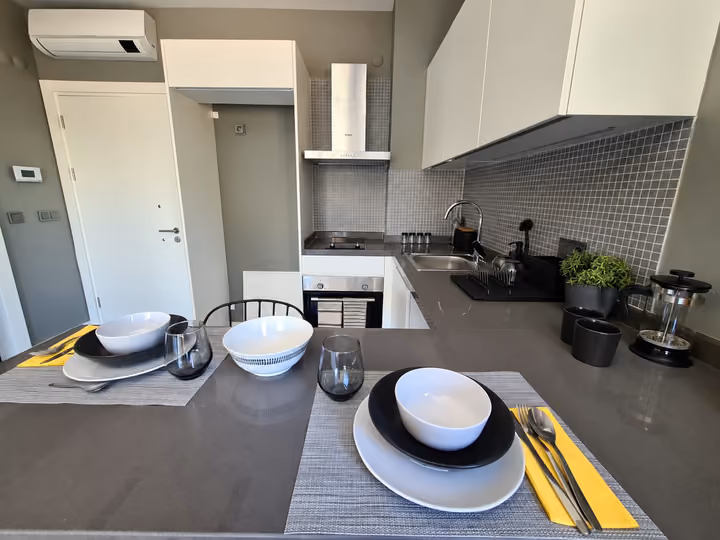 Photograph of a kitchen with a breakfast counter, stools and fitted cabinetry.