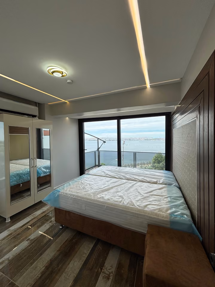 Furnished bedroom opening towards a sea-view balcony.