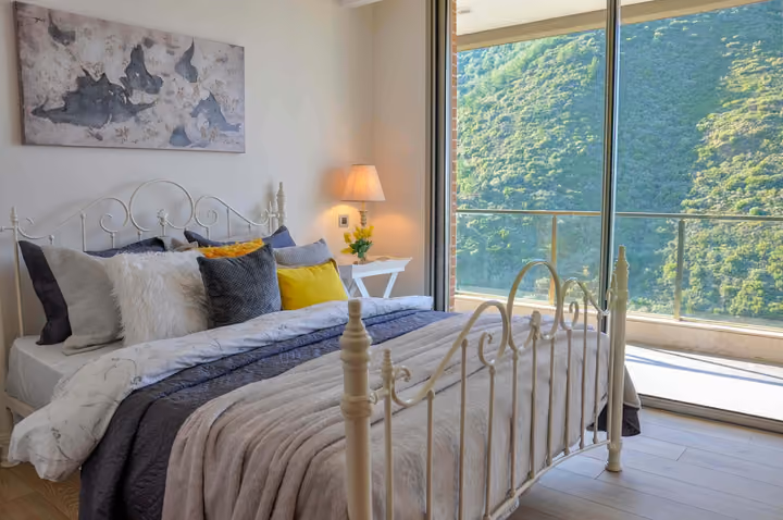 Bedroom with wide windows facing the wooded valley.