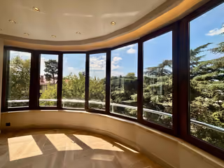 Curved living room windows with a view of mature trees.
