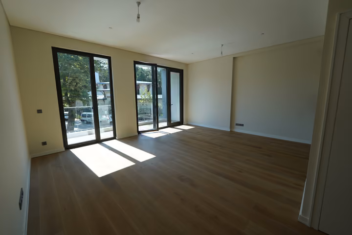 A wide view of the living room with sunlight entering through two glazed balcony openings.