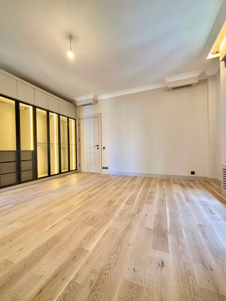 Alternate bedroom view with illuminated glass-front wardrobes.