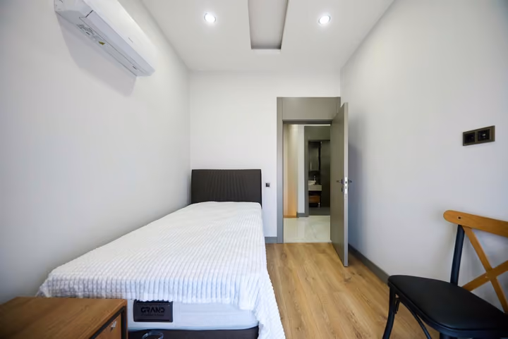 Single bedroom with a bed, desk, radiator and air conditioning.