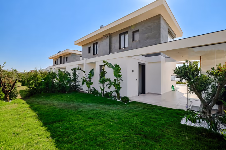 Detached villa exterior with balconies, stone cladding and landscaped garden in Ardıç, Çeşme.