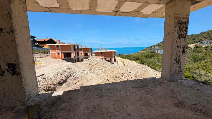 An unfinished concrete interior with broad openings toward construction and the sea. Undated photograph supplied in the construction source folder; it does not establish the current completion status.