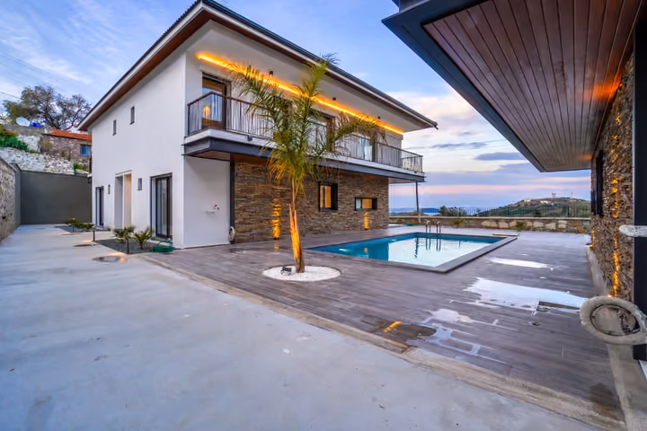Oblique view across the courtyard toward a two-storey villa, palm tree and rectangular shared pool with open views beyond the boundary.