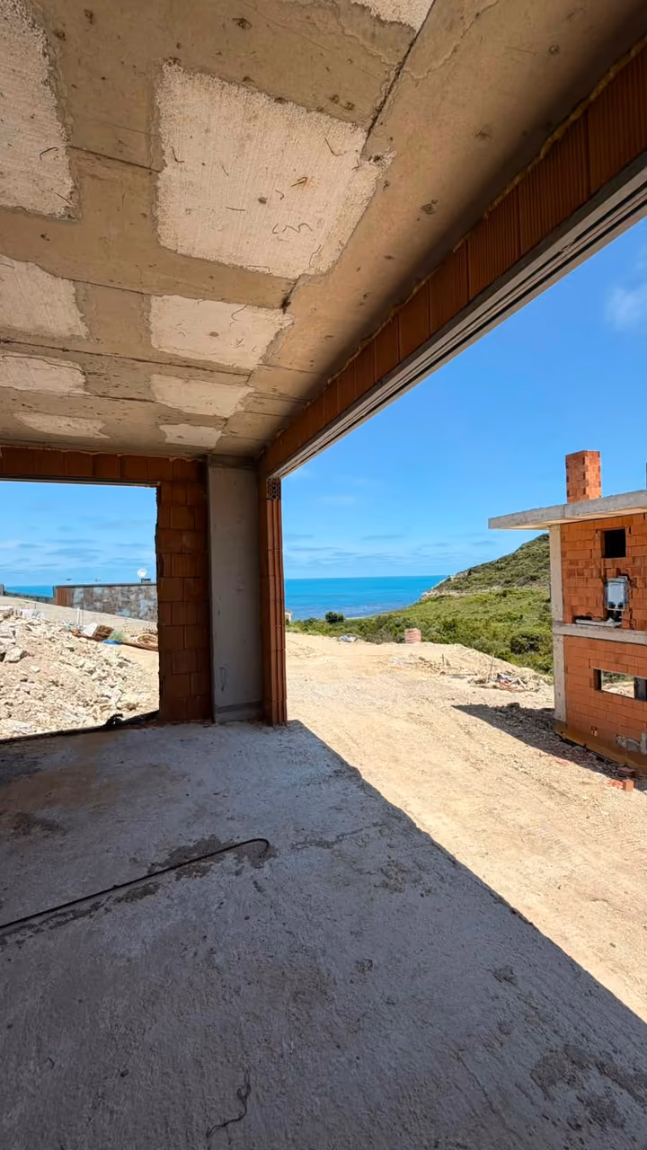 An unfinished room overlooking neighbouring construction and the sea. Undated photograph supplied in the construction source folder; it does not establish the current completion status.