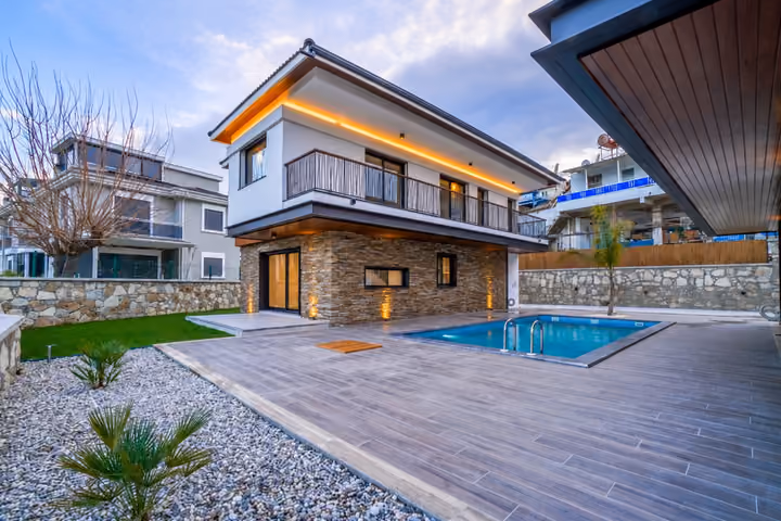 Two-storey villa with a long upper balcony, a rectangular swimming pool, tiled terrace and gravel planting beds.