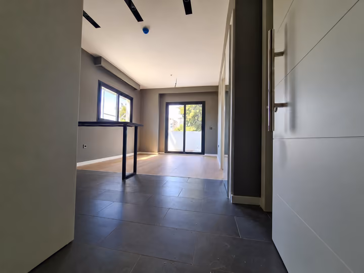 Photograph of an unfurnished open-plan room with kitchen fittings and glazed doors.