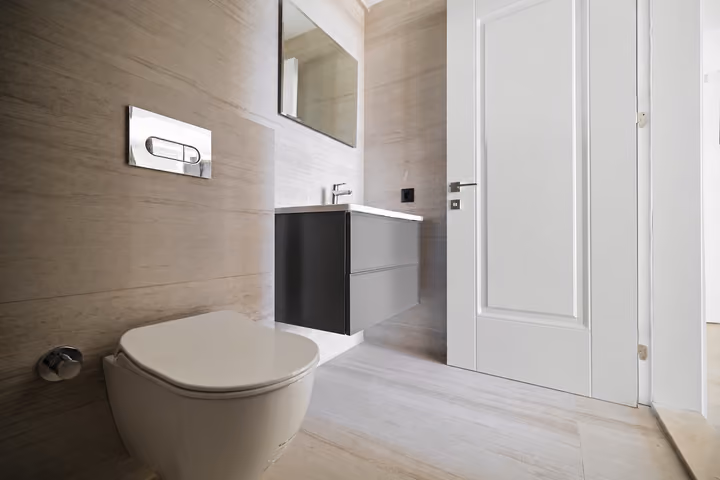 Bathroom with a wall-hung toilet and dark vanity unit.