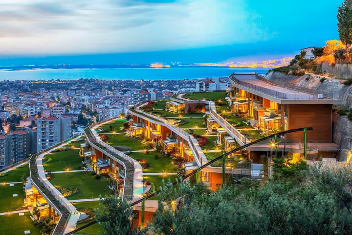 Terraced hillside residences overlooking Izmir Bay at dusk.