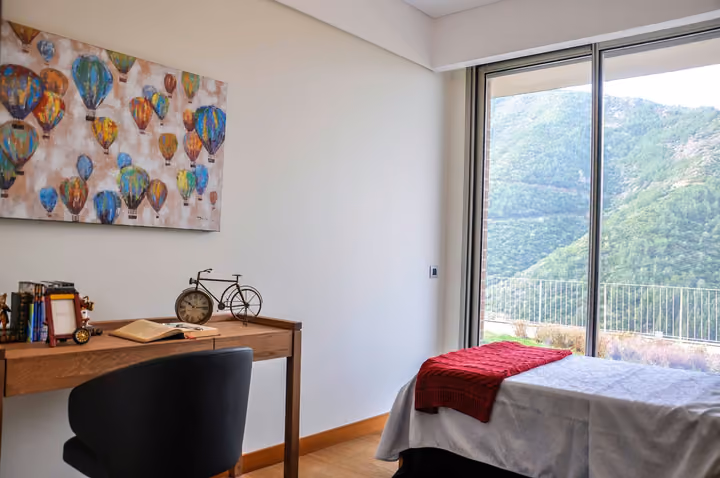 Bedroom with a desk and hillside views.