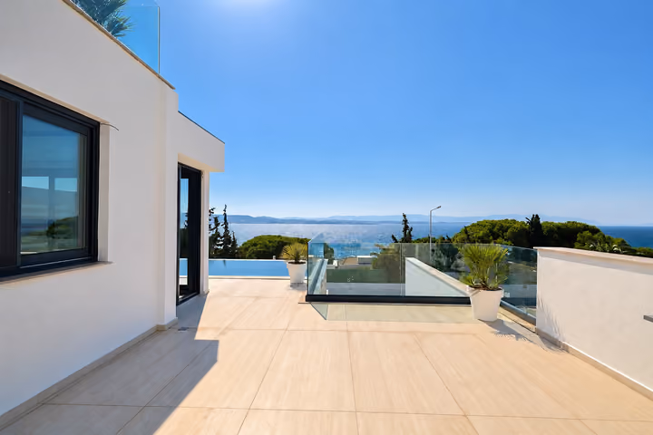 Sea-facing terrace with glass balustrades beside the private pool.