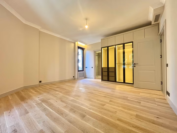 Bedroom with illuminated glass-front wardrobes and an adjoining bathroom doorway.