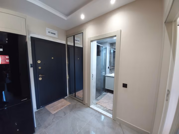 A furnished show apartment entrance with mirrored storage and an adjoining bathroom doorway.