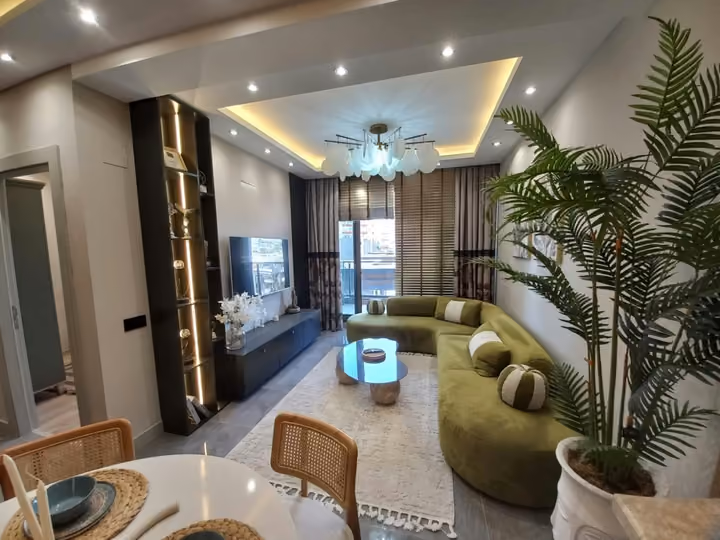 A show apartment living room with green seating and balcony doors.
