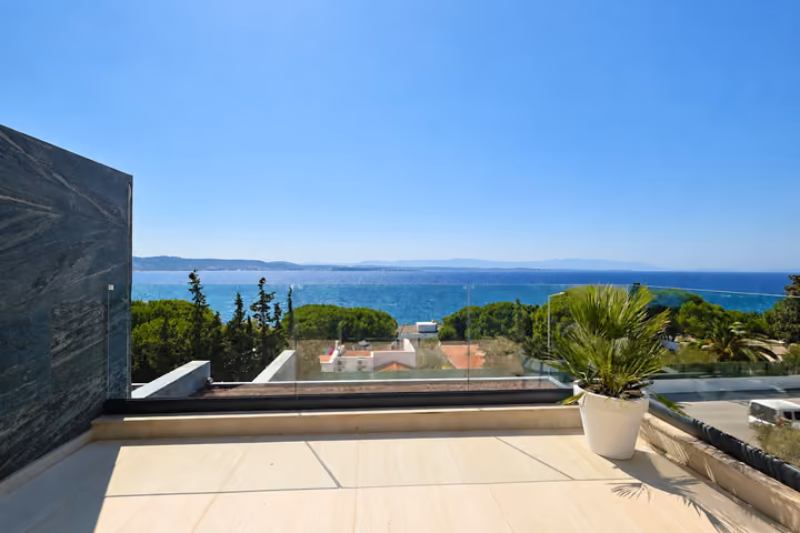 Panoramic sea view from a terrace with glass balustrades.