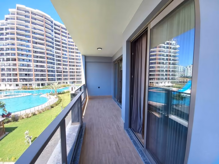 A photographed show apartment balcony facing the shared pool and residential buildings.