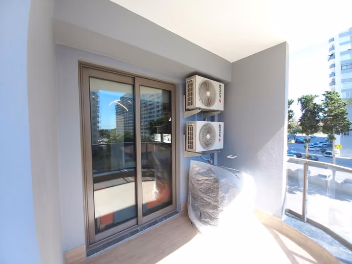 A photographed balcony with glazed doors and external air-conditioning units.