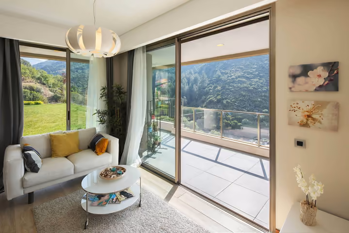 Living room opening onto a balcony with forest views.