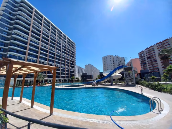 The curved edge of the outdoor pool with residential buildings behind it.