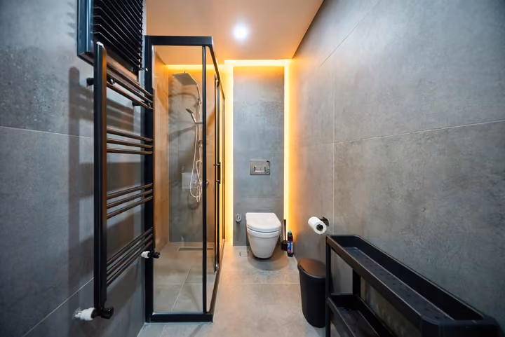 First bathroom with an enclosed shower, toilet and a wall-mounted towel radiator.