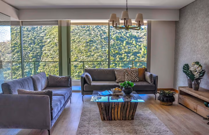Living room with broad windows facing green hills.