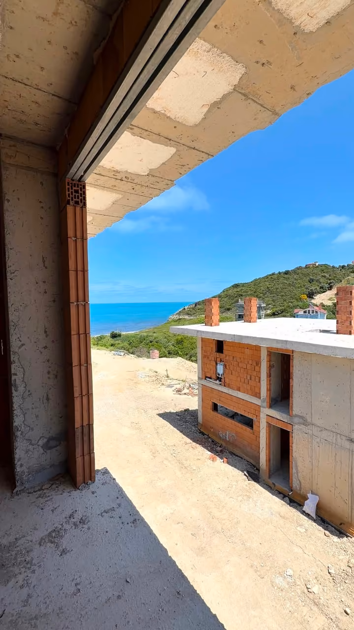 An unfinished side opening overlooking nearby construction and the sea. Undated photograph supplied in the construction source folder; it does not establish the current completion status.