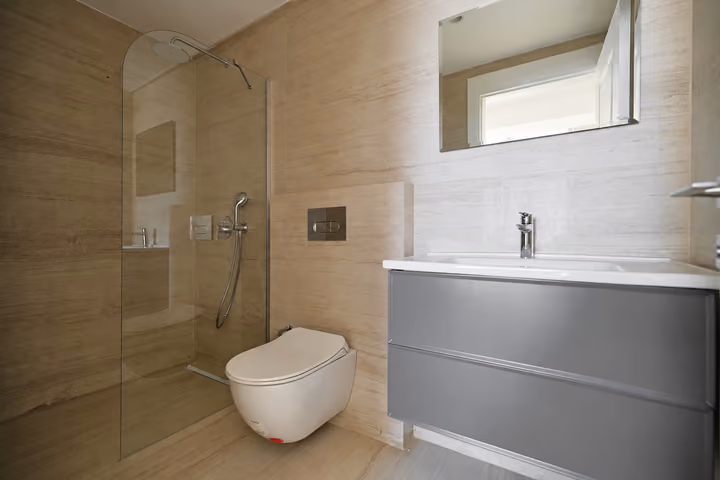 Bathroom with a glass shower enclosure, vanity and wall-hung toilet.