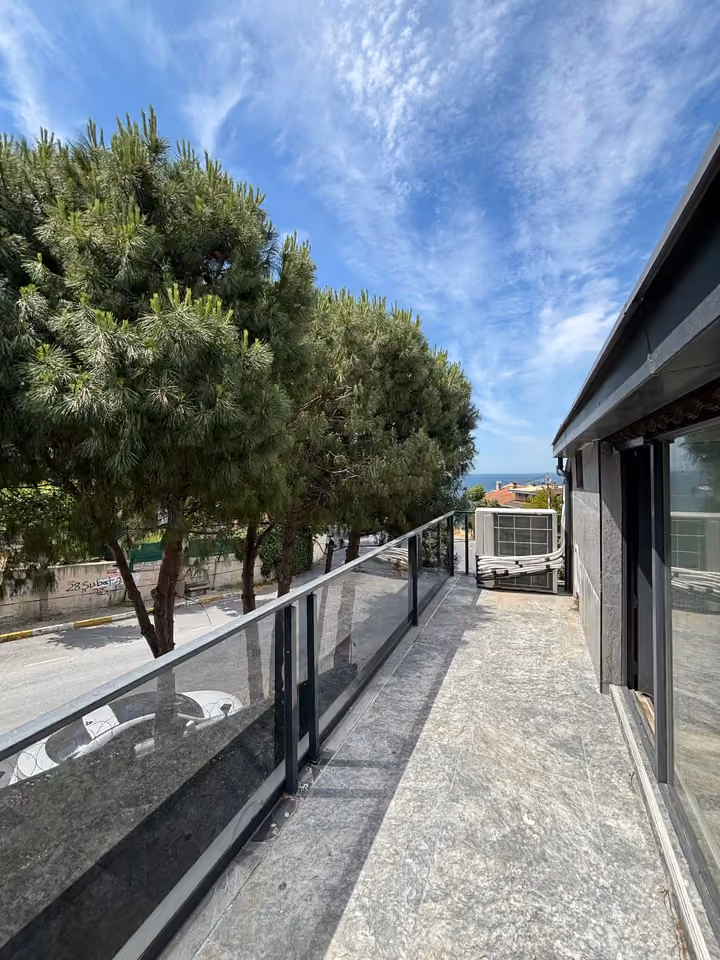 Upper balcony with glass railings beside the villa.