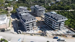 Exterior photograph of four blocks and courtyard work in Oba Alanya in February 2026