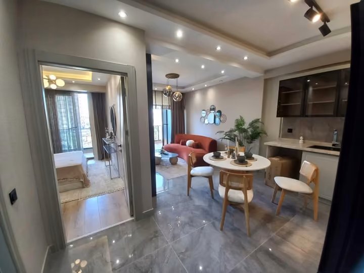 View into a furnished show apartment kitchen and dining space from the entrance.