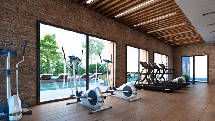Rendering of a fitness room with cardio equipment beside full-height windows.