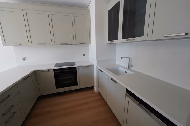The U-shaped fitted kitchen with a light worktop, built-in oven and sink.