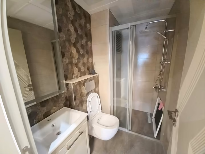 A show apartment bathroom with a glass shower, toilet and basin.