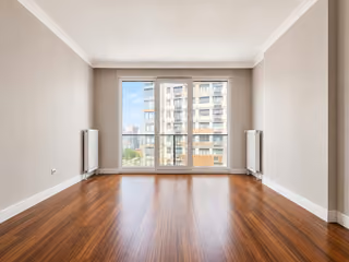 Empty living room with wood flooring and a wide full-height window.