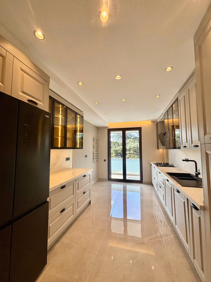Kitchen with white cabinetry, dark appliances and glazed doors toward the balcony.