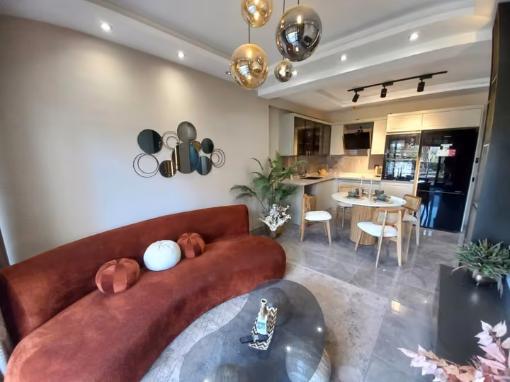 Furnished show apartment living room with a red sofa and open kitchen beyond.