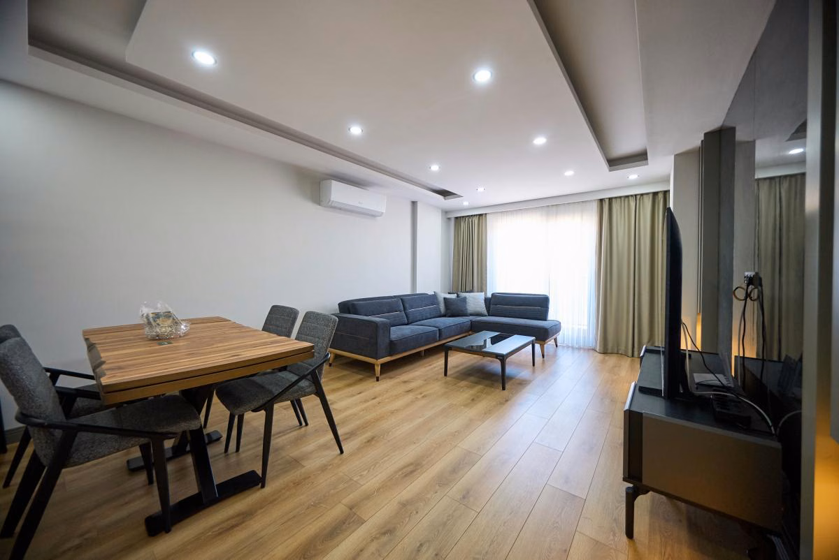 Furnished living and dining room with a sofa, dining table and balcony doors.