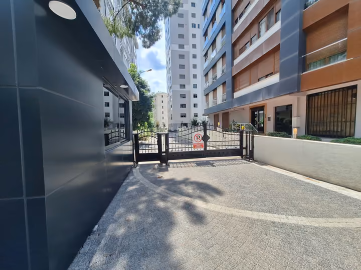 Apartment building entrance and gated driveway beside a guard booth.