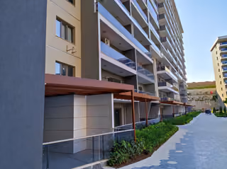 Photograph showing balconies, ground-floor terraces and the planted walkway beside the building.