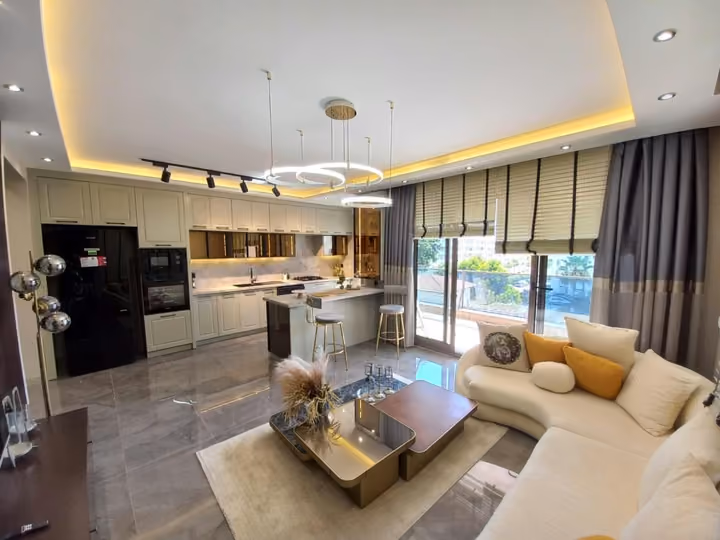 A wide view of a show apartment kitchen, island and furnished lounge.