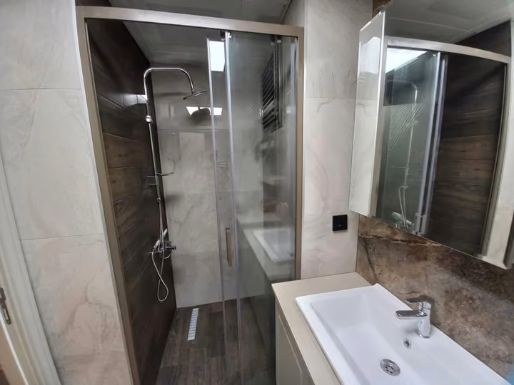A glass shower enclosure, basin and mirrored cabinet in a show apartment bathroom.