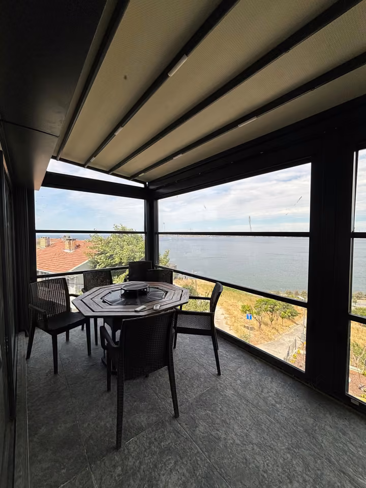 Enclosed terrace with a dining table and sea views.